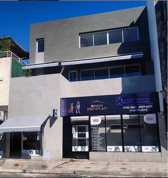 El frente gris de la veterinaria, con el cartel azul oscuro y la vidriera